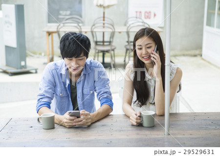 カフェでスマホを使う20代男女 29529631