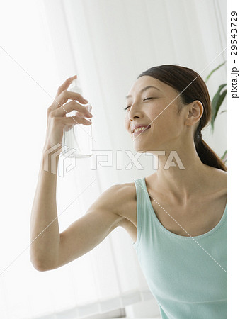 顔にスプレーをする女性の写真素材