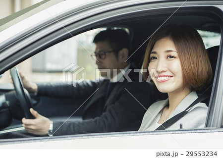 助手席に座る笑顔の女性と運転する男性の写真素材