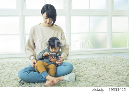 リビングで携帯を覗く親子 29553425