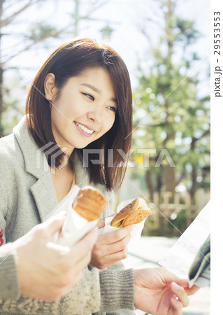 おやつを片手に持ち地図を確認する20代女性 29553553
