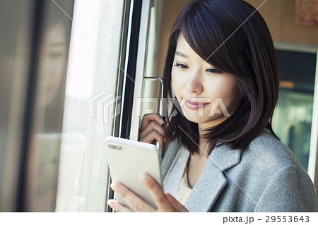 電車内で携帯電話を見る代女性の写真素材