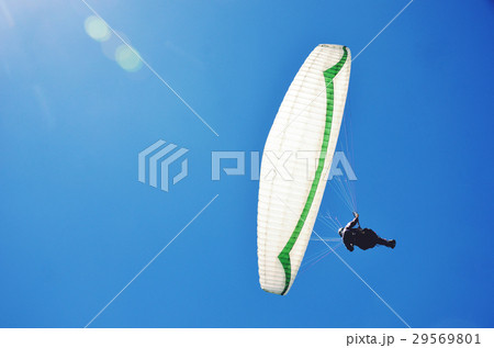 Paraglider soaring through clear blue sky 29569801