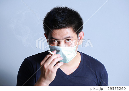 young man smoking cigarette with  protective mask 29575260