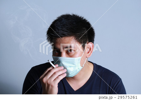 young man smoking cigarette with  protective mask 29575261
