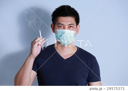 young man smoking cigarette with protective mask young man smoking cigarette with protective mask 29575271