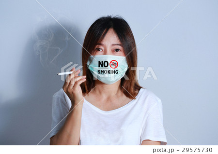 young woman smoking cigarette with  protective mas 29575730