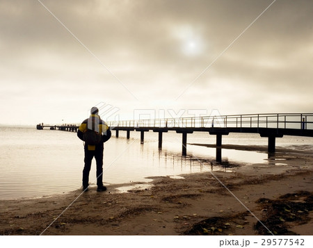Hiker with backpack alone on sandy beach, sunrise Hiker with backpack alone on sandy beach, sunrise 29577542