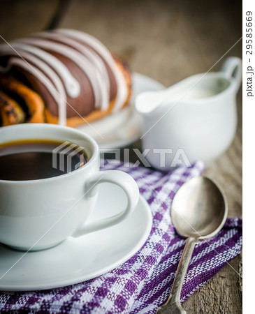Cup of coffee and poppy bun glazed with ganache 29585669
