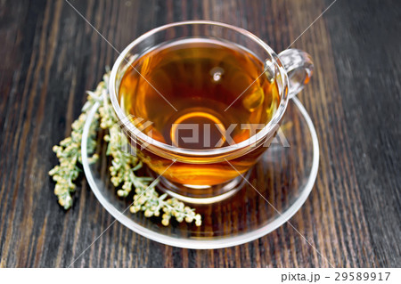 Tea with gray wormwood in glass cup on dark board 29589917