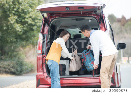車から荷物を下ろす夫婦の写真素材