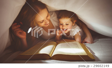 Mother and child read book under blanket with a flashlight. 29602149