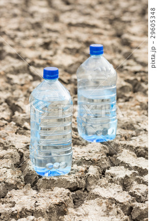 Bottle with water on the dried ground. Global 29605348