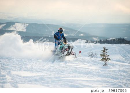 Rider on the snowmobile in the mountains 29617096