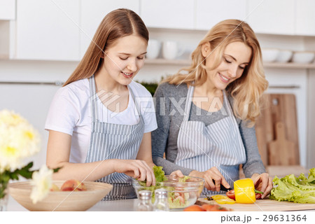 Smiling teenage girl and her mother cooking on the Smiling teenage girl and her mother cooking on the 29631364