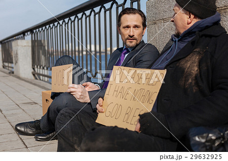 Two men sitting on the pavement from despair Two men sitting on the pavement from despair 29632925