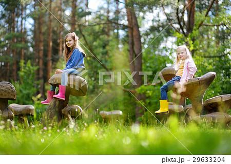 Two cute little sisters having fun on giant wooden mushrooms 29633204