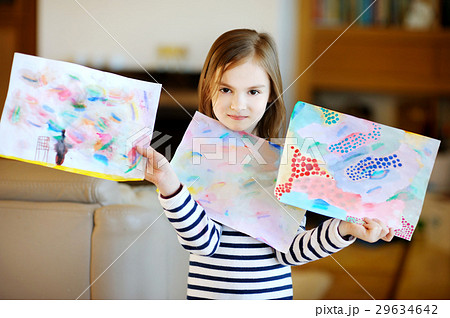 Portrait of cute little girl showing her drawings Portrait of cute little girl showing her drawings 29634642