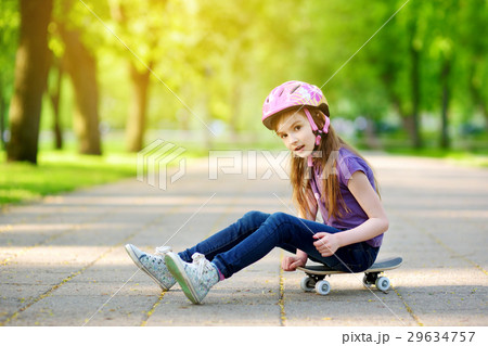 Cute little preteen girl wearing helmet sitting on a skateboard Cute little preteen girl wearing helmet sitting on a skateboard 29634757