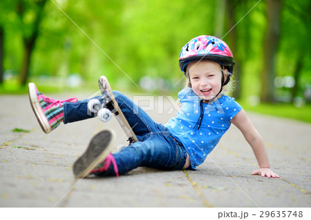 Pretty little girl learning to skateboard outdoors 29635748