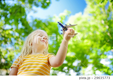 Adorable little girl playing with small toy airplane outdoors Adorable little girl playing with small toy airplane outdoors 29635773