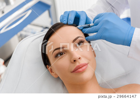 Happy female getting injection in forehead 29664147