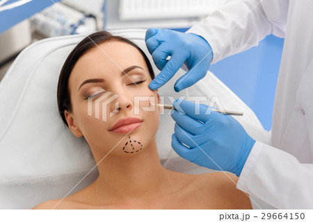 Doctor drawing correction marks on calm woman Doctor drawing correction marks on calm woman 29664150