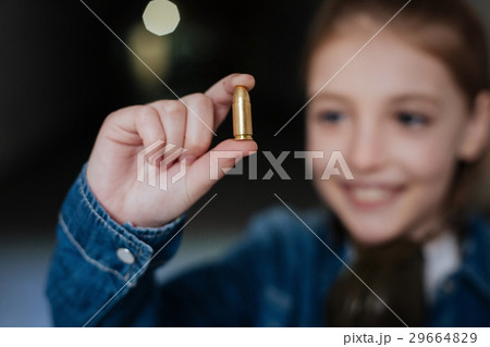 Selective focus of a bullet being held by a girl Selective focus of a bullet being held by a girl 29664829