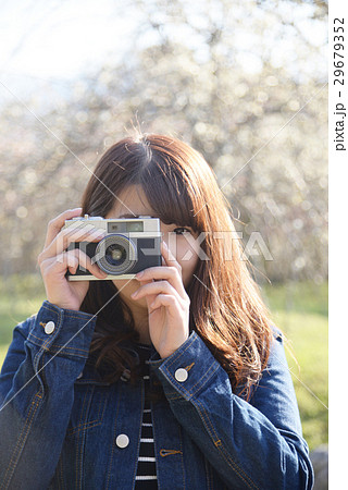 カメラ女子 カメラ 一眼レフ レトロ 女性 代 桜 目線 花 ロング 長髪 かわいい の写真素材