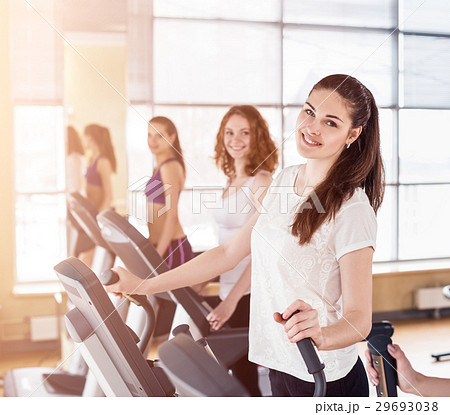 Young women running on treadmill in gym. Young women running on treadmill in gym. 29693038