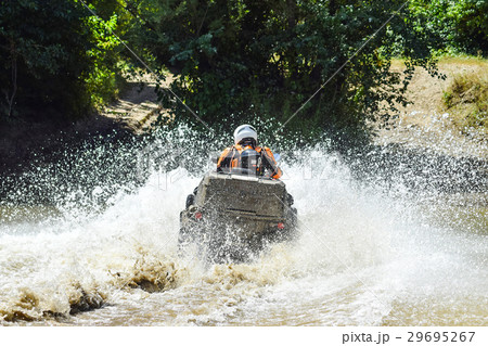 The man on the ATV crosses a stream The man on the ATV crosses a stream 29695267
