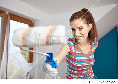 Beautiful young woman painting wall in room 29695502