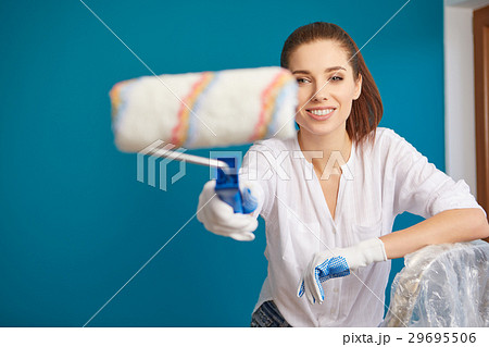 Beautiful young woman painting wall in room 29695506