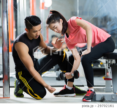 Trainer men are teaching woman lifting a dumbbell Trainer men are teaching woman lifting a dumbbell 29702161