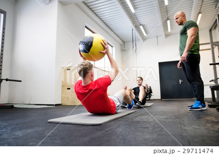 Men in gym with trainer exercising with medicine 29711474