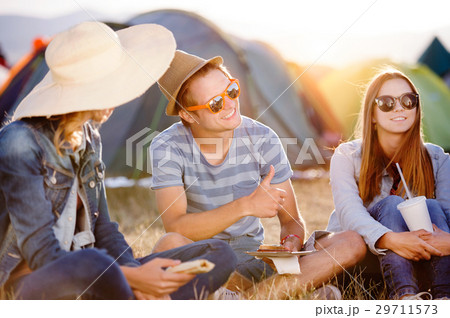 Teenagers sitting on the ground in front of tents 29711573