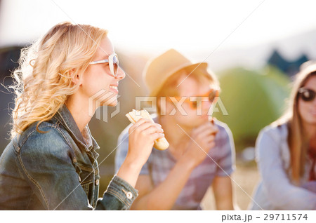 Teenagers sitting on the ground in front of tents Teenagers sitting on the ground in front of tents 29711574