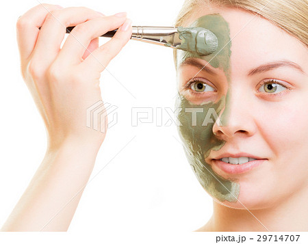 Woman applying with brush clay mud mask her face 29714707