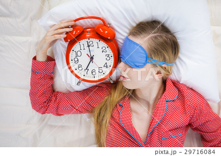 Sleeping woman wearing pajamas holding clock Sleeping woman wearing pajamas holding clock 29716084