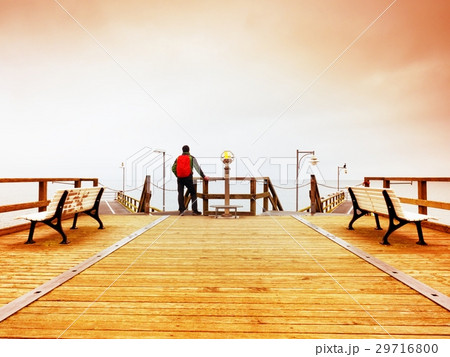 Tourist walk in autumn mist on wooden sea pier Tourist walk in autumn mist on wooden sea pier 29716800