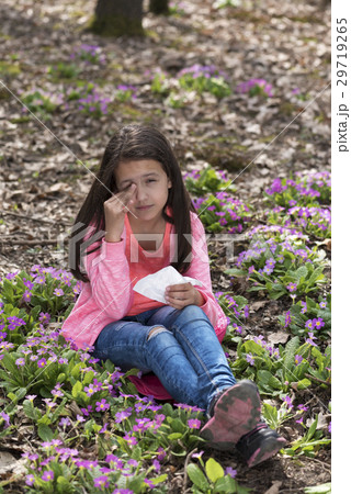 Girl with allergic rhinitis sitting among primrose 29719265