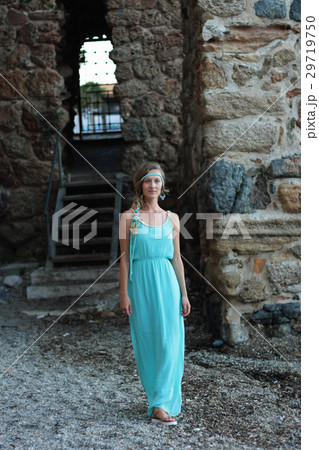 Young woman walking against blurred background of medieval stone Young woman walking against blurred background of medieval stone 29719750