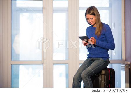 Woman with suitcase and tablet after traveling at Woman with suitcase and tablet after traveling at 29719793