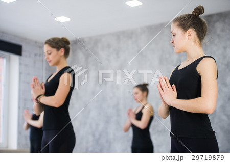 Female trainer with class standing in namaste pose Female trainer with class standing in namaste pose 29719879