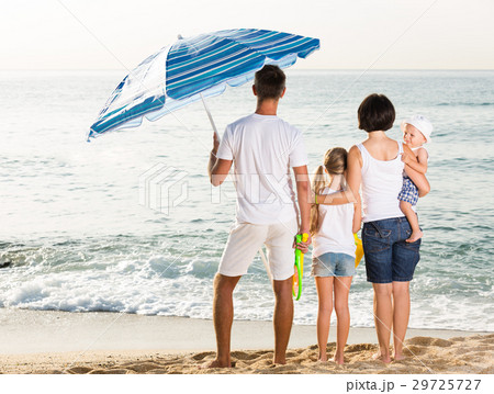 back view on family of four standing on beach . back view on family of four standing on beach . 29725727