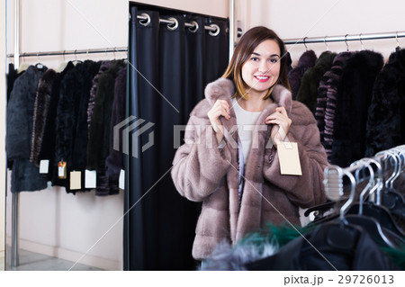 Pretty girl customer trying on new fur coat Pretty girl customer trying on new fur coat 29726013