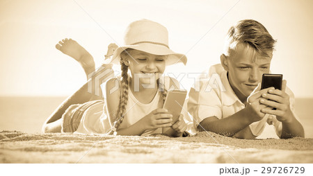 Smiling kids on beach with phone in hands Smiling kids on beach with phone in hands 29726729