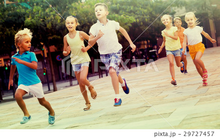 kids actively playing and running together on street on summer d 29727457