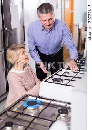happy mature couple chooses in shop of household appliances gas stove with oven 29727813