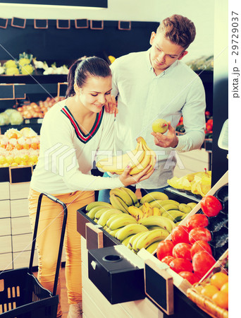 Glad adult couple deciding on fruits in shop 29729037